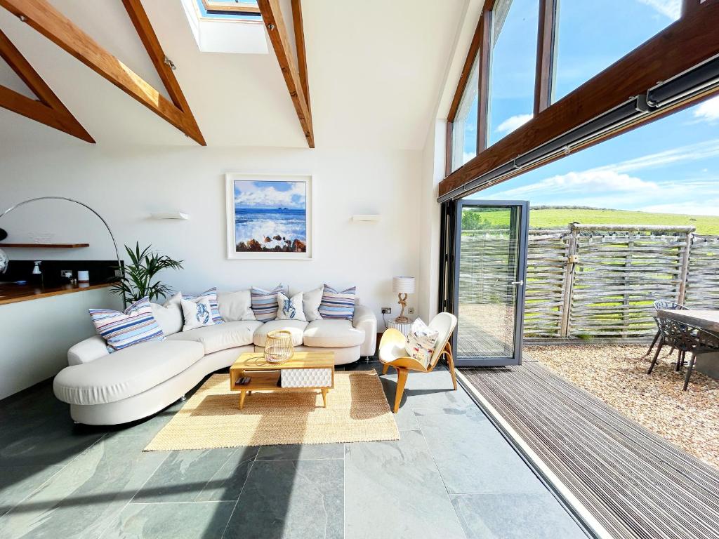 ein Wohnzimmer mit einem weißen Sofa und einem Tisch in der Unterkunft Merlin Farm Cottages short walk to Mawgan Porth Beach and central location in Cornwall in Mawgan Porth