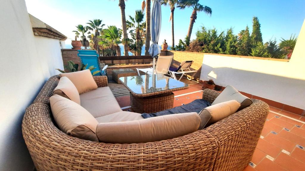 um pátio com um sofá de vime e uma mesa em Loma del Rey 56 - casa primera linea de mar em La Alcaidesa