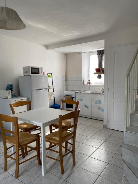 a kitchen with a white table and chairs at Appartement 1 chambre et cuisine VIERVILLE-SUR-MER,plage du Débarquement in Vierville-sur-Mer