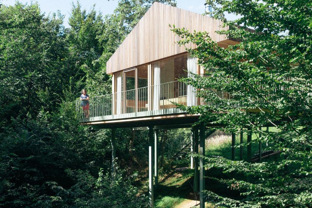 a woman standing on the deck of a tree house at baumhaus buchengrün in Dobl-Zwaring