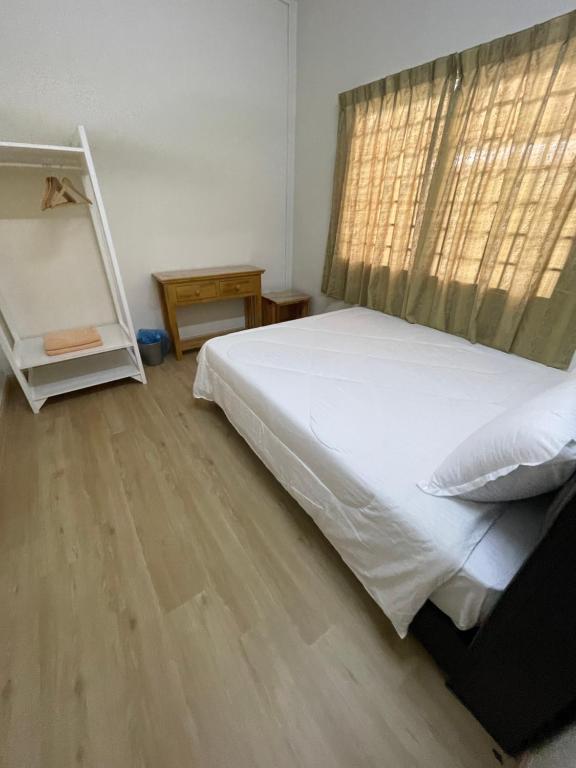 um quarto com uma cama branca e piso em madeira em SEA LA VIE SWEET @ NAUTICA RESORT em Porto Dickson