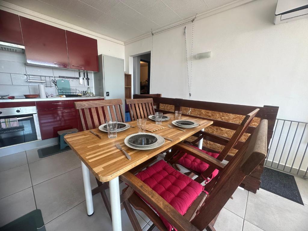 a wooden table with red cushioned chairs in a kitchen at Appartement T2 Colombier pour 5 personnes vue mer in Sainte-Clotilde