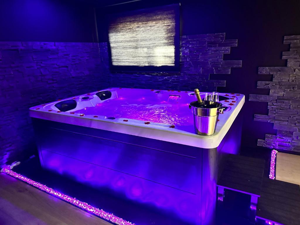 Flers-en-Escribeus的住宿－Homesuiteandspa，紫色灯光客房内的紫色浴缸