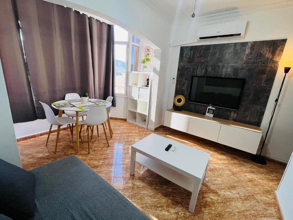 - un salon avec une télévision, une table et des chaises dans l'établissement Casa V&T Torremolinos, à Torremolinos