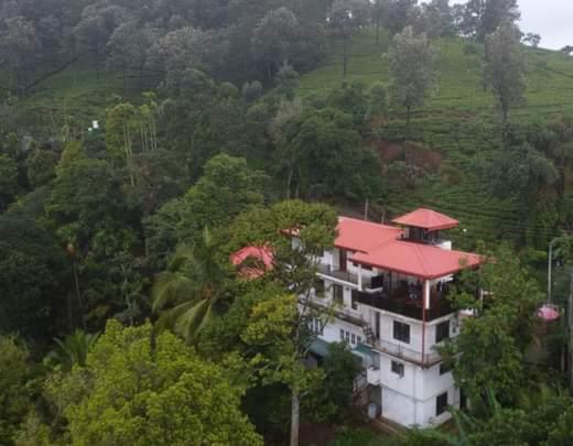una casa con techo rojo en medio de un bosque en Villa 95 Rangala, en Kandy