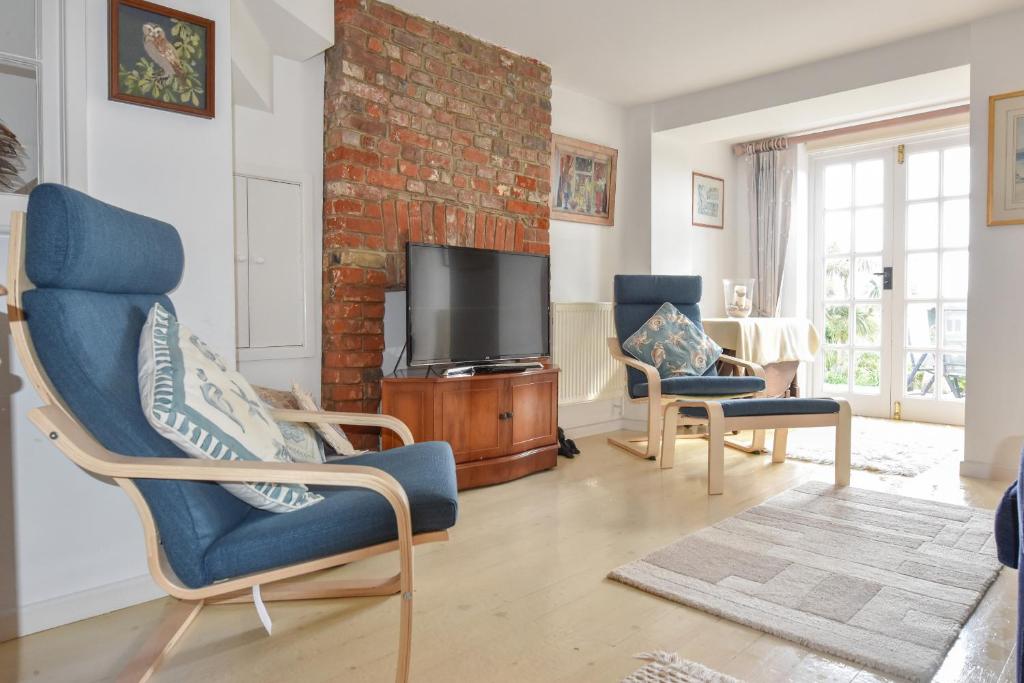 een woonkamer met twee stoelen en een tv bij Mulberry Cottage in Cowes