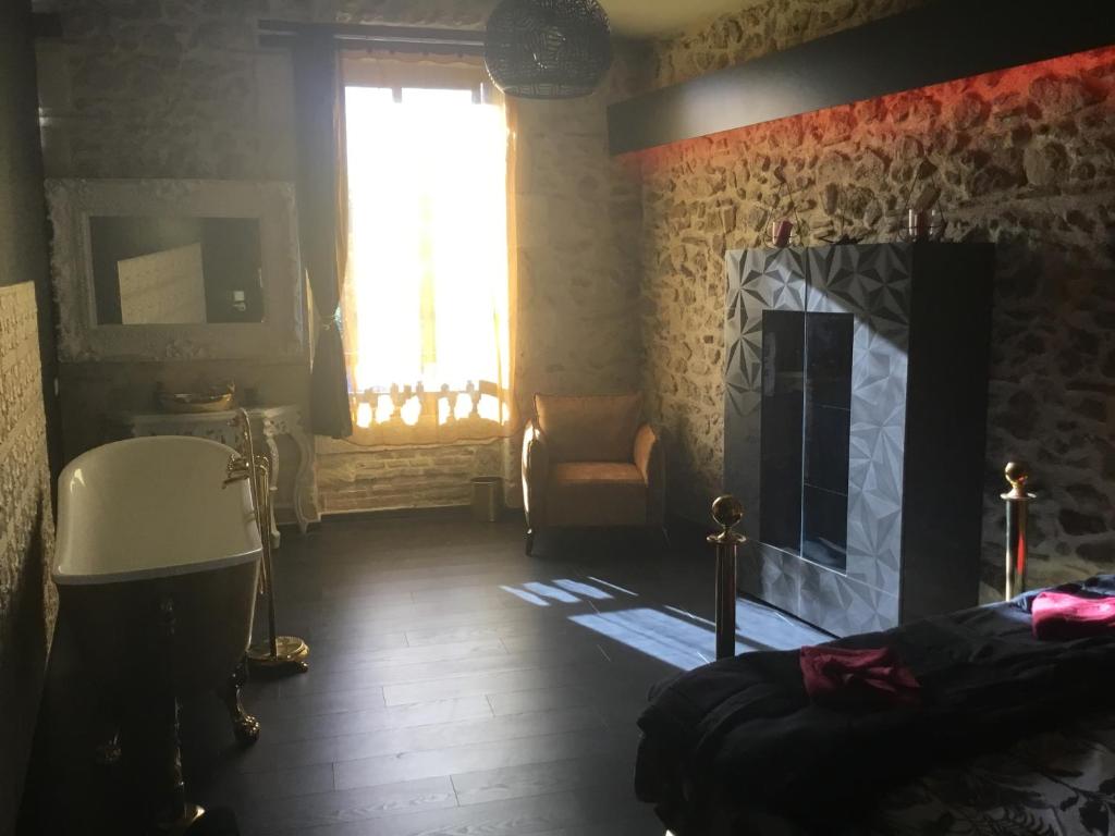 1 dormitorio con chimenea, 1 cama y ventana en CHEZ PAM agréable chambre d’hôte pour les amoureux en Marmande