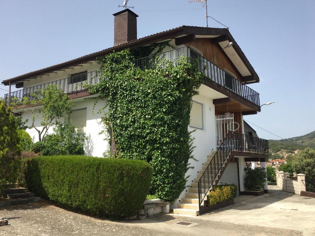 Una casa blanca con hiedra a un lado. en Chalet Camino Verde, 