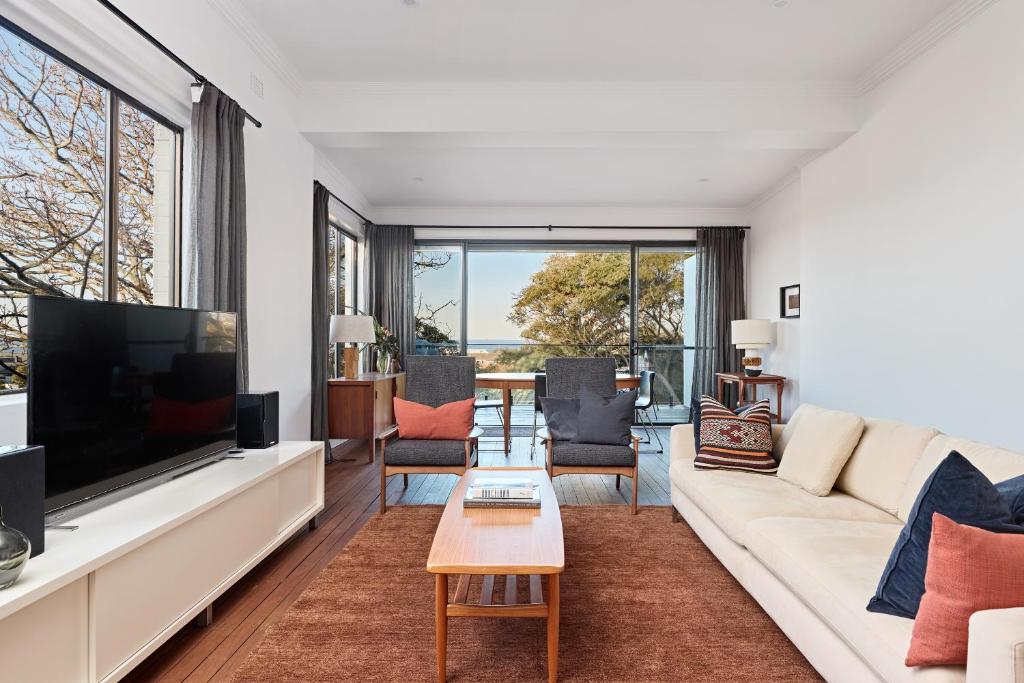 a living room with a white couch and a large tv at Coogee Treetops in Sydney