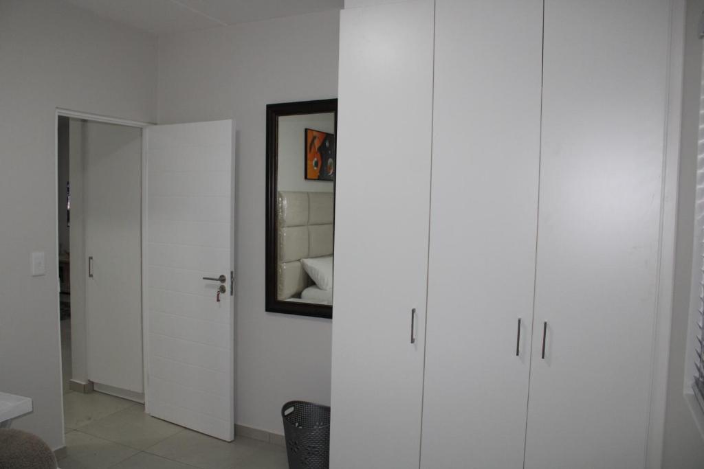 a white room with white cabinets and a mirror at Fun modern two bed apartment in fourways in Sandton