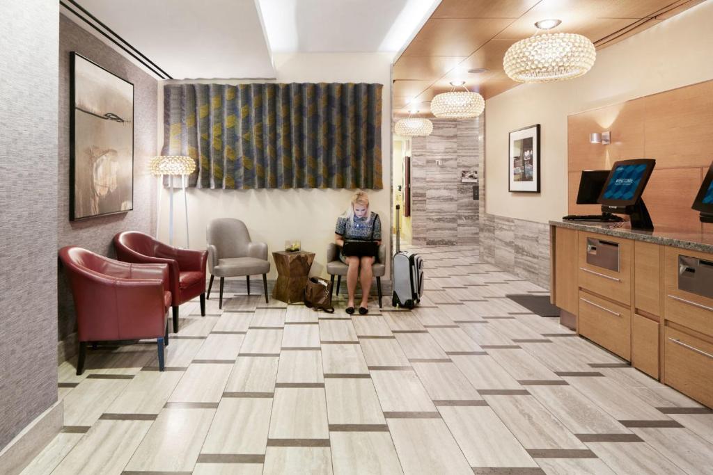 a woman standing in a waiting room at a hospital at The Jewel Hotel, New York in New York