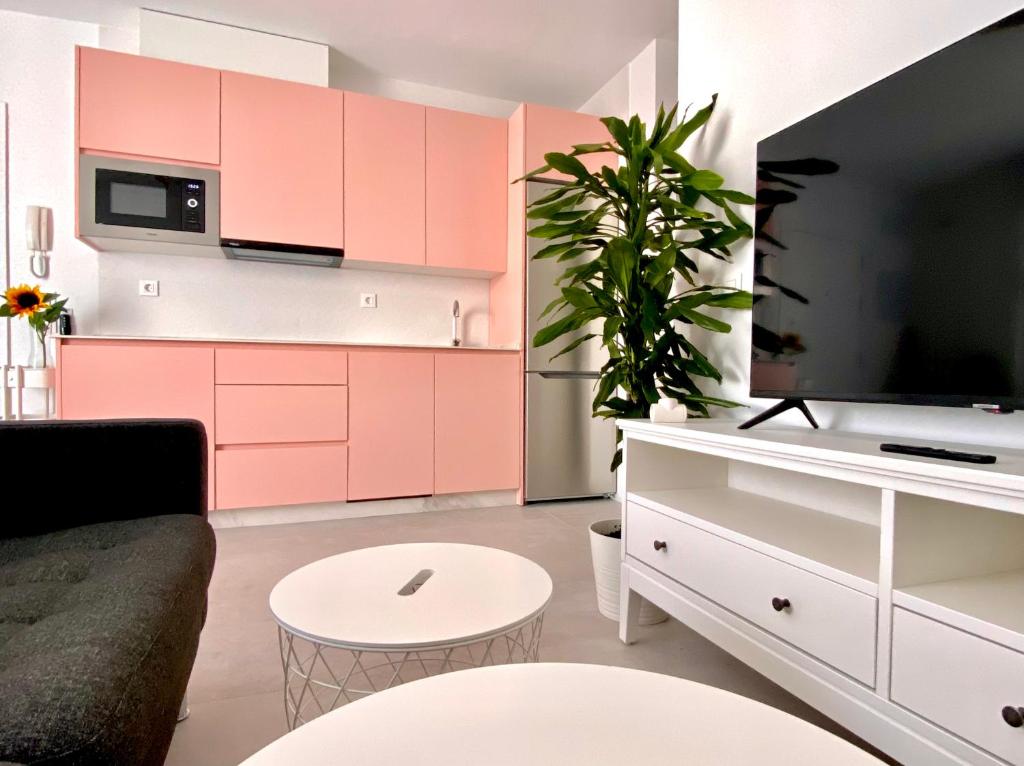 uma sala de estar com armários cor-de-rosa e uma televisão em Apartamento Luz de Conil. WIFI+A/C. SOLO FAMILIAS Y PAREJAS em Conil de la Frontera