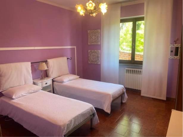 een paarse kamer met 2 bedden en een raam bij Villa Aurora in Fosdinovo