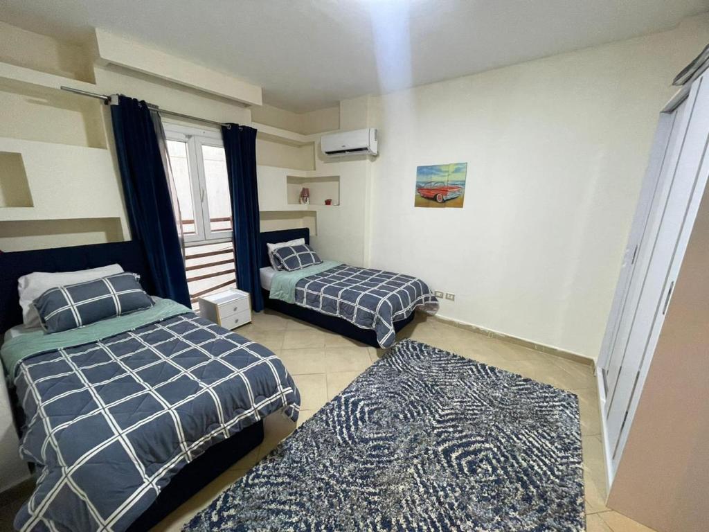 a bedroom with two beds and a rug at شقة للايجار كمبوند زايد ديونز in Sheikh Zayed