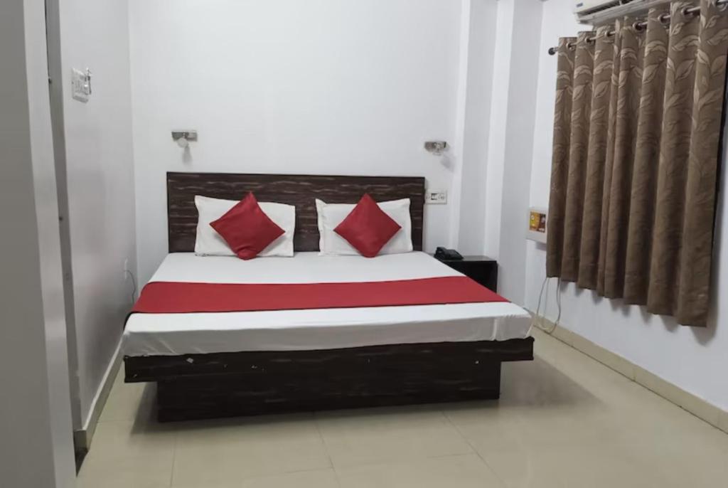 a bedroom with a large bed with red pillows at GRG Kanha Inn Lucknow in Lucknow