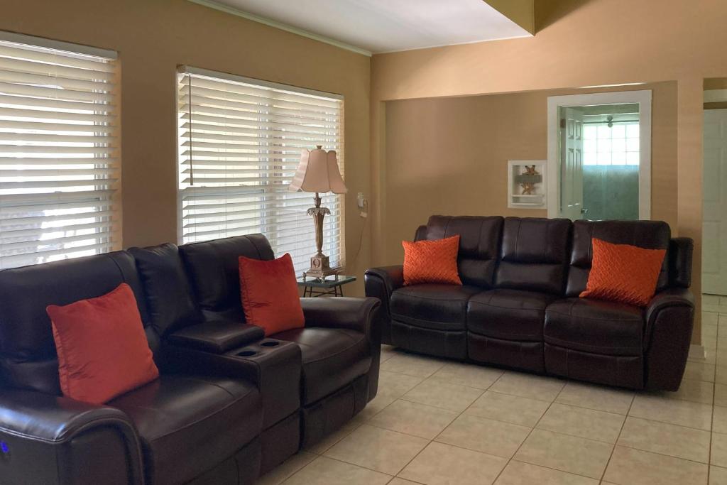 Home near the beach & golf with inviting patio, fireplace, AC, & washer/dryer في فرناندينا بيتش: غرفة معيشة مع أريكتين من الجلد الأسود ووسائد برتقالية