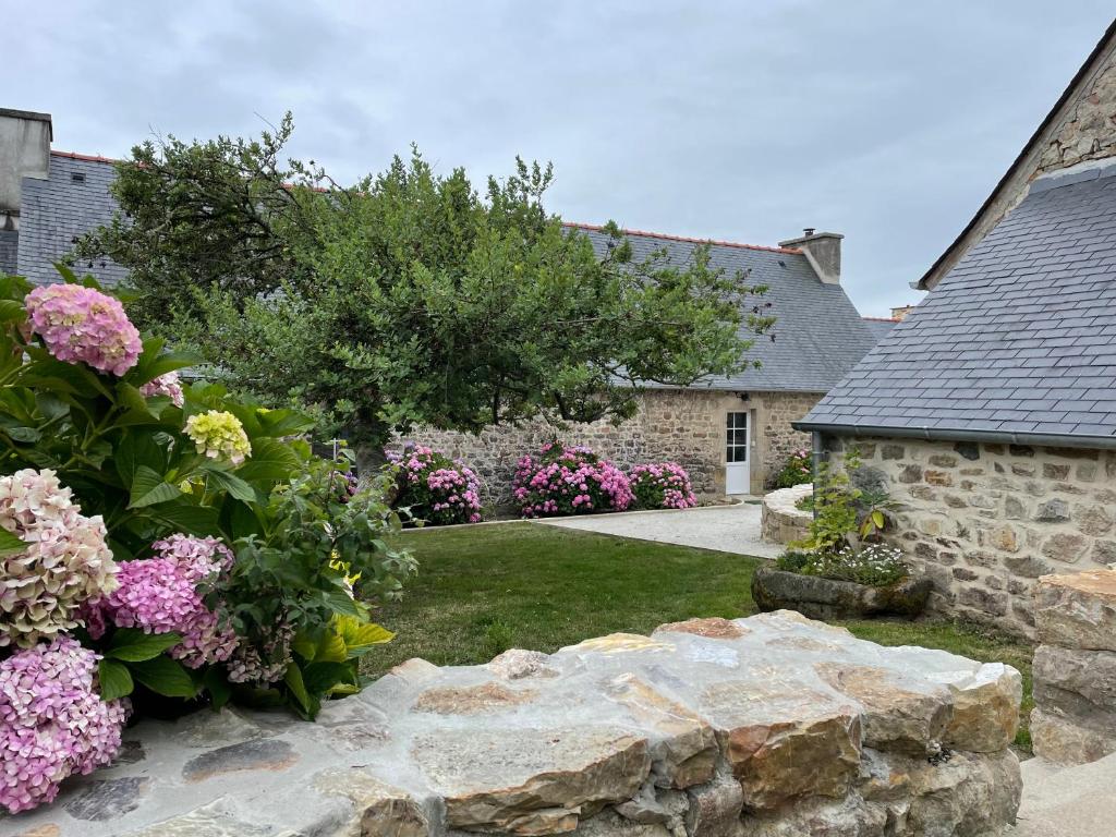 um jardim com flores e uma parede de pedra em Les Cottages du Manoir, Jacuzzi -Crozon em Crozon