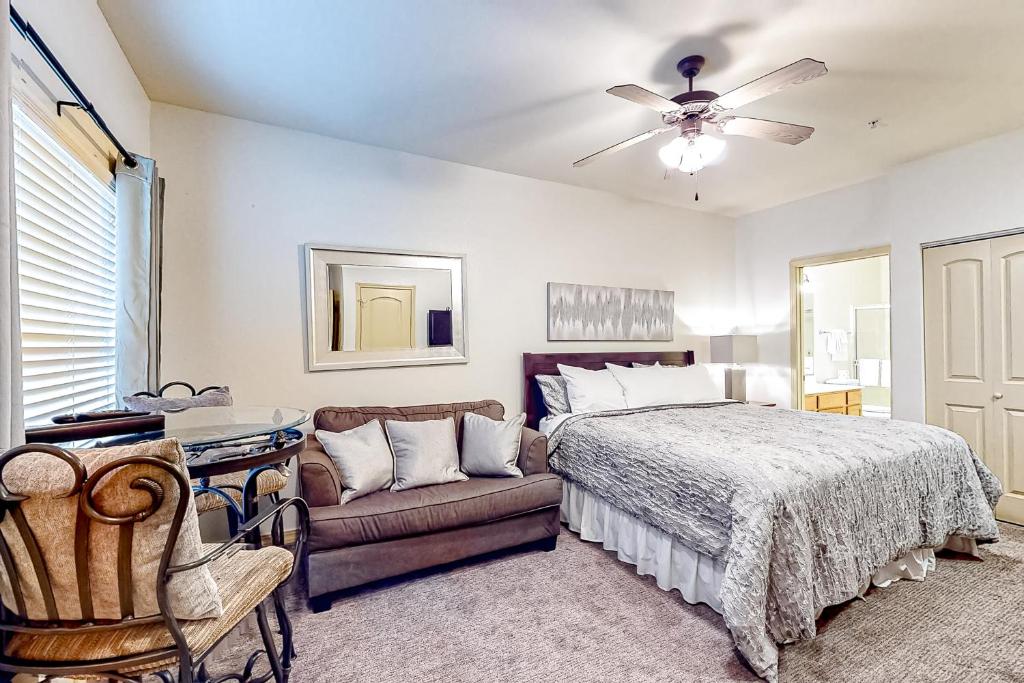 a bedroom with a bed and a couch and a ceiling fan at Wildwood Adventures - Unit B in Branson