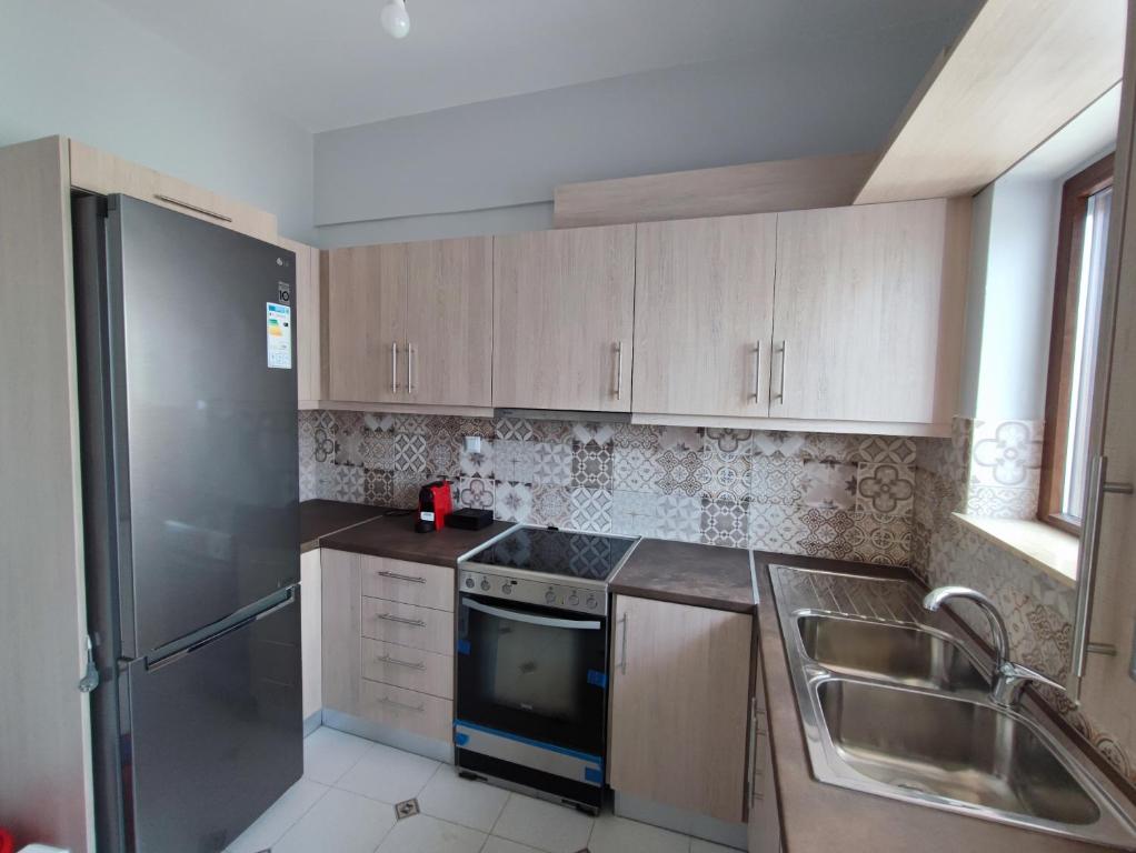 a kitchen with wooden cabinets and a stainless steel refrigerator at Watch Penthouse City Center & parking in Chania
