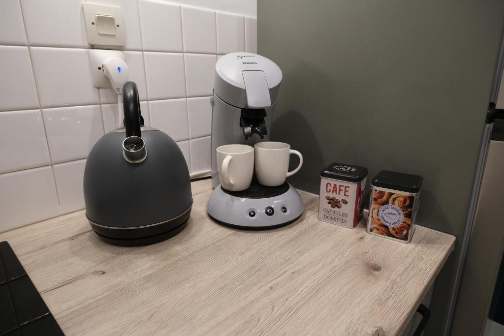 a counter with a coffee maker and two cups on it at Le Jockey - SIPCO Immobilier - Centre in Saint Lo