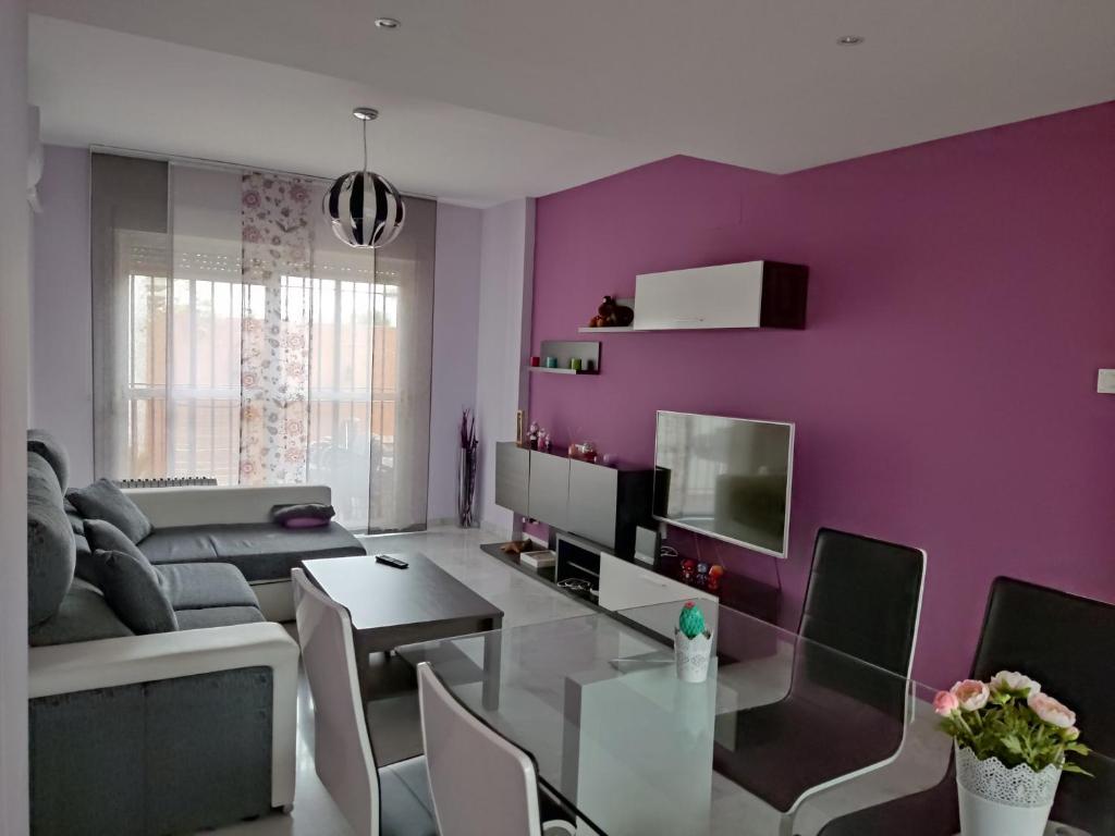 una sala de estar con una pared de color púrpura y una mesa. en Acogedora casa adosada, en Alhendín