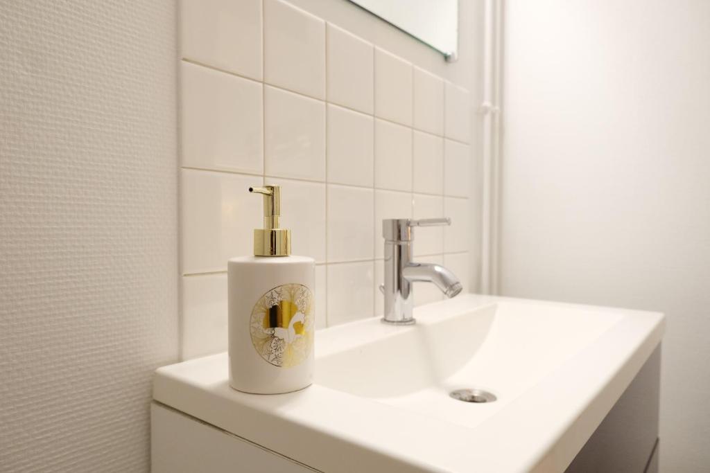 a white bathroom with a sink and a mirror at Le Jockey - SIPCO Immobilier - Centre in Saint Lo