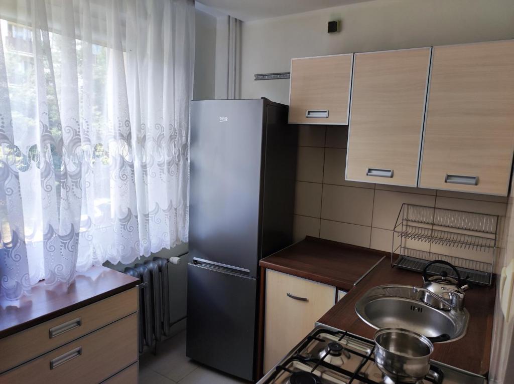 a small kitchen with a sink and a refrigerator at Apartament na Wyszyńskiego - mieszkanie w centrum Myszkowa dla firm i nie tylko in Myszków