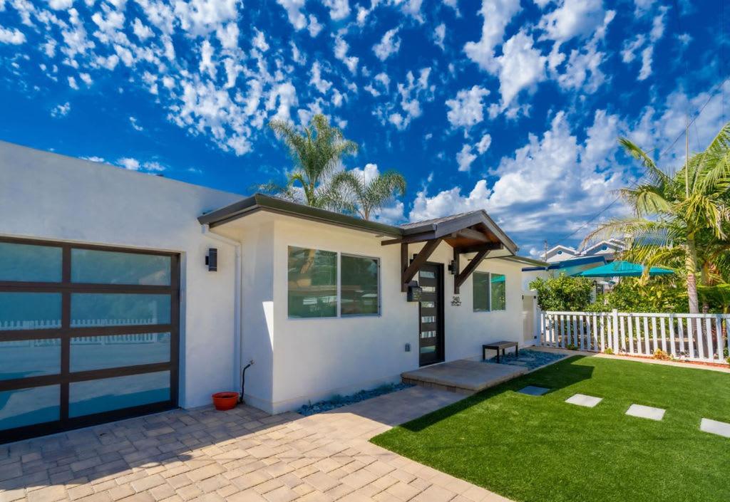 une maison blanche avec une pelouse et une clôture dans l'établissement Coronado Bayside Charmer, à San Diego