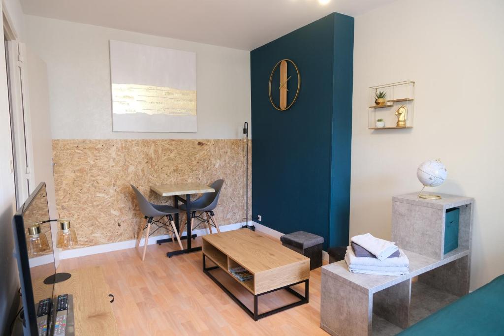 a living room with a blue wall and a table at Le Jockey - SIPCO Immobilier - Centre in Saint Lo