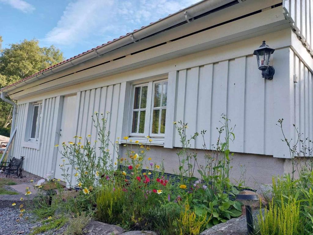 a white house with flowers in front of it at Cozy studio near sea, forest and town in Brastad