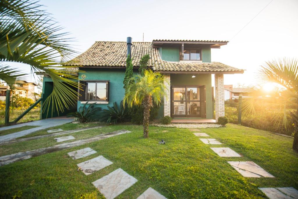 a house with a palm tree in the yard at Casa na Barra de Ibiraquera in Barra de Ibiraquera