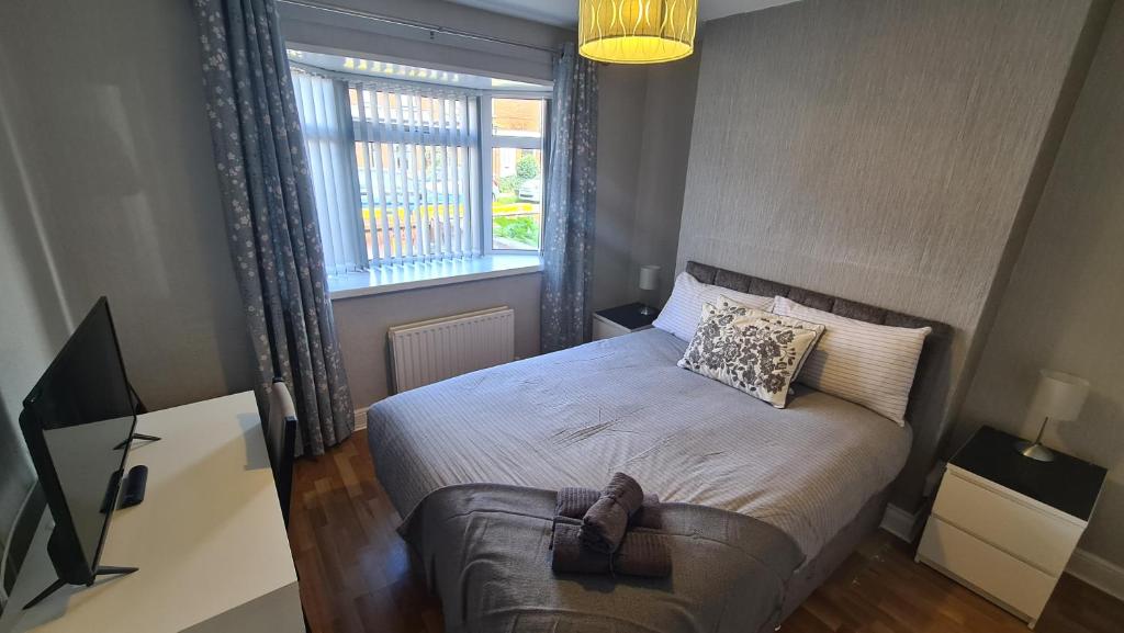 um pequeno quarto com uma cama e uma janela em Ravenhill Townhouse Belfast em Belfast