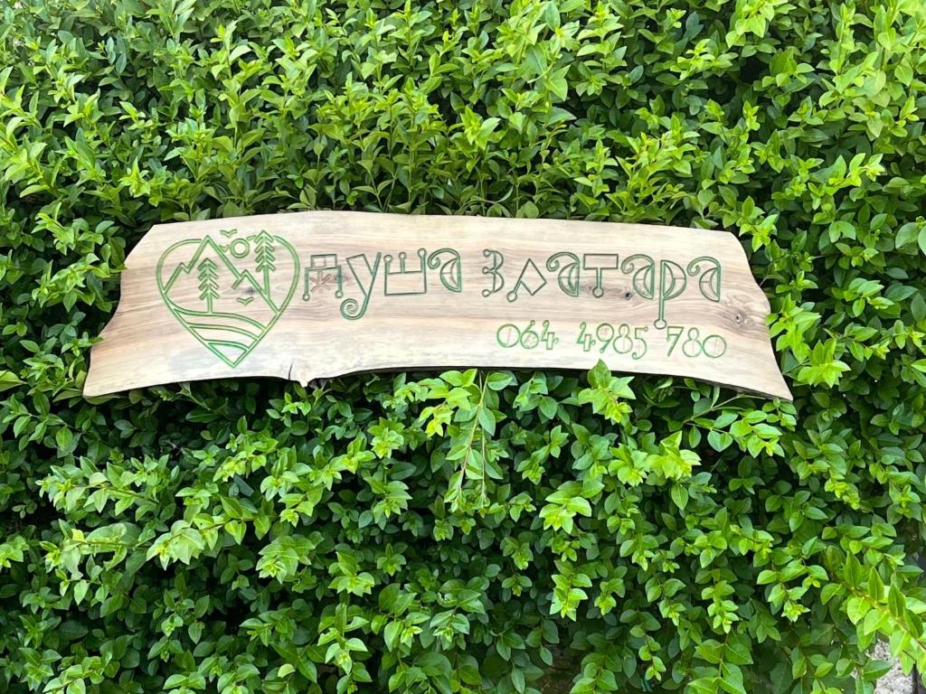 a wooden sign in a hedge with a sign at Duša Zlatara in Nova Varoš