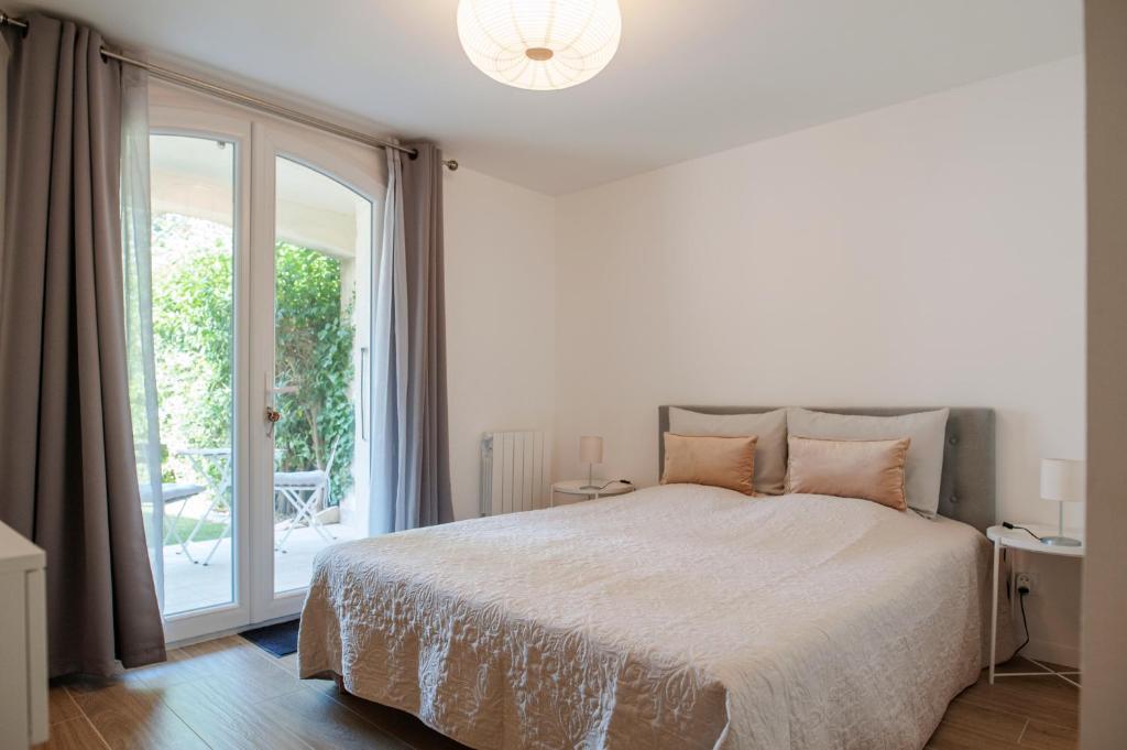 a white bedroom with a bed and a sliding glass door at Le Solaret in Sète