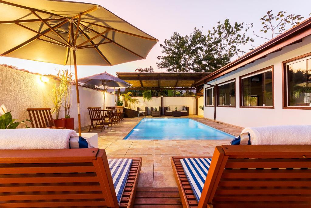 a swimming pool with two beds and an umbrella at Pousada Recanto do Jabaquara in Paraty