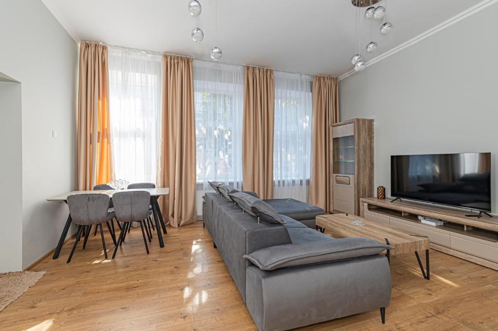 un salon avec un canapé, une télévision et une table dans l'établissement Prestigious city center apartment with free parking by Polo Apartments, à Kaunas
