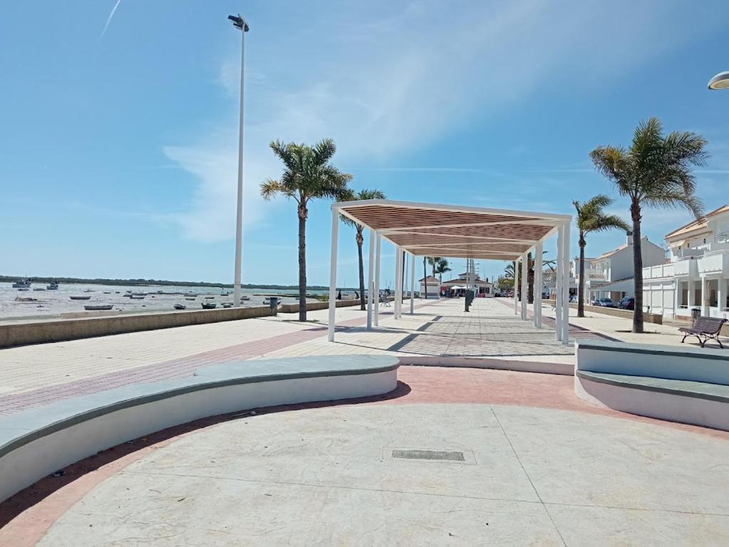 ein Bürgersteig mit einem Pavillon neben dem Strand in der Unterkunft Cornise in El Rompido