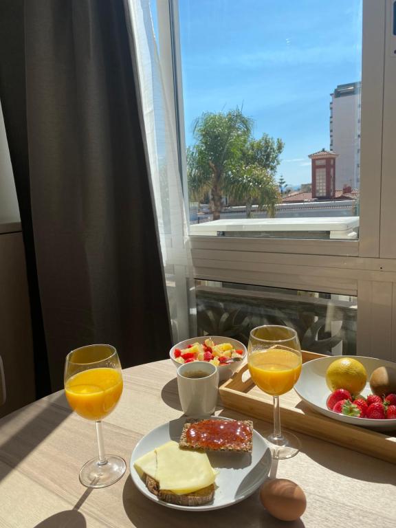 - une table avec un plateau de nourriture et 2 verres de jus d'orange dans l'établissement Studio La Carihuela, à Torremolinos