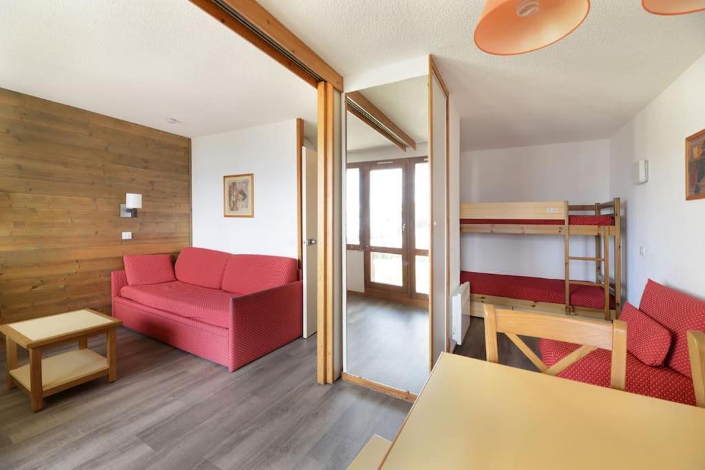 a living room with a red couch and a bunk bed at Studio 28m2 vue pistes plein sud du dimanche au dimanche in La Plagne