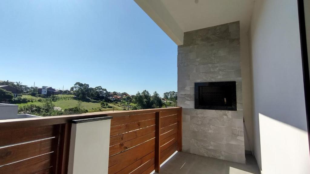 a balcony with a television and a stone wall at Suítes do Vale - Praia do Rosa in Imbituba