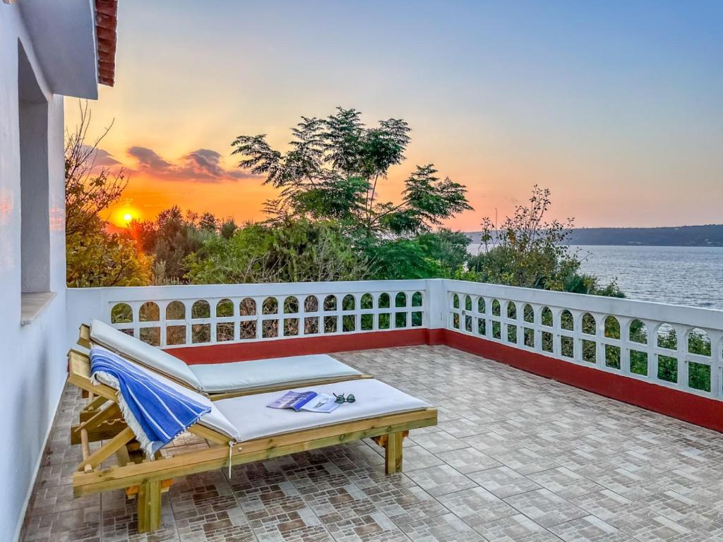 un balcón con un banco y una puesta de sol en el fondo en Fisherman's House, en Sinoikismós Plakálona