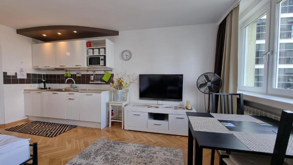 een keuken en een woonkamer met een tafel en een televisie bij Like Home Flat B in Warschau