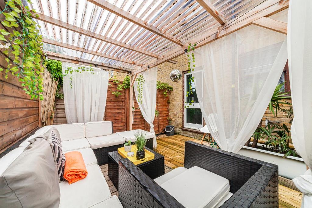 a patio with a white couch and a pergola at 2BED Garden house w/Hot Tub, Sauna & Cinema room in London