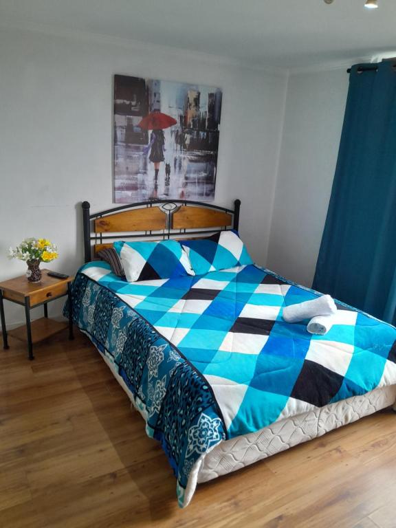 a bedroom with a bed with a blue and white comforter at Apartamento tipo estudio acogedor entre metro católica y baquedanono in Santiago