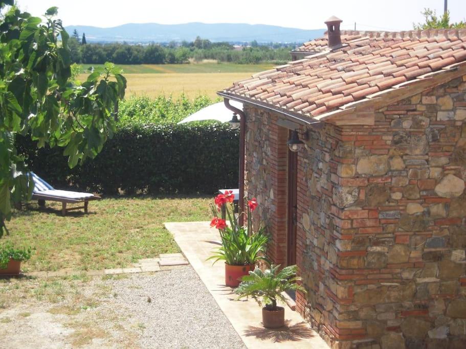 een bakstenen gebouw met bloemen en een bank in een tuin bij Monolocale per due Agriturismo le Pinete in Riotorto