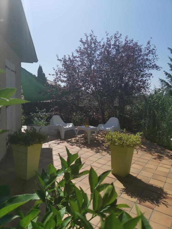 un patio avec des chaises blanches, des tables et des plantes dans l'établissement La provence, à Saint-Prim