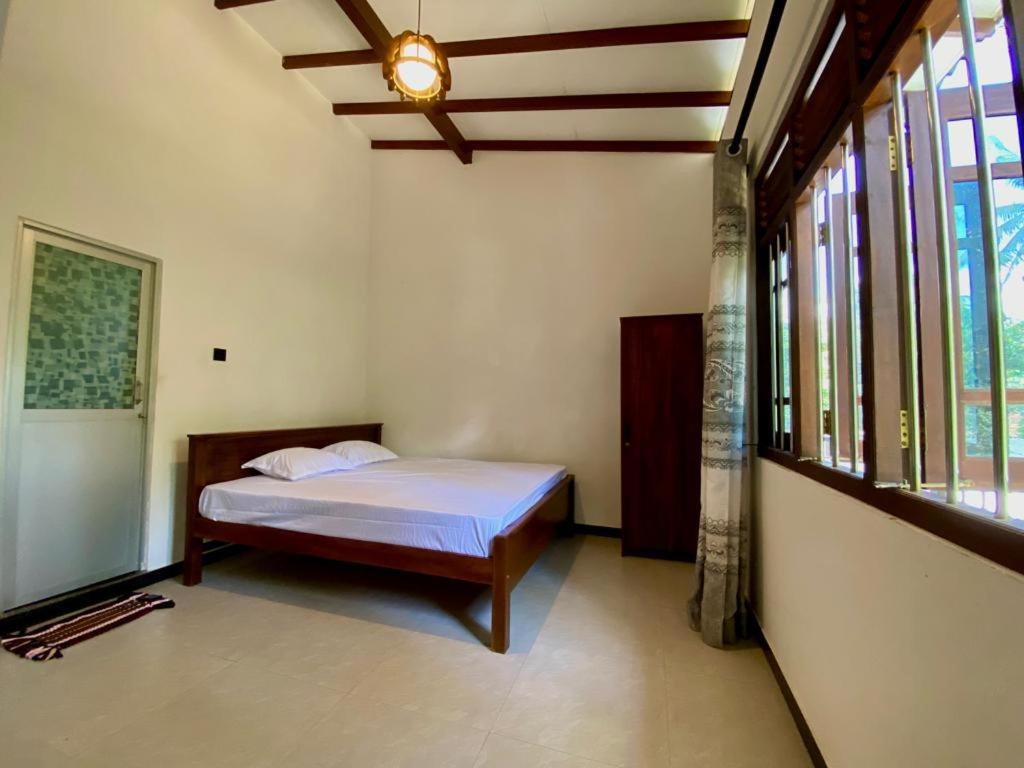 ein Schlafzimmer mit einem Bett in einem Zimmer mit Fenstern in der Unterkunft Home Stay Polhena in Matara