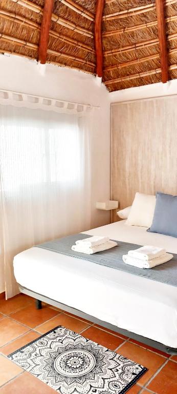 a bedroom with a large white bed with a rug at Mandala Bungalows - Adults Only in Los Caños de Meca