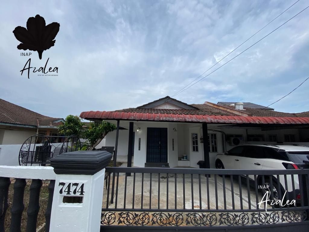 a house with a gate and a car in front of it at Homestay Azalea in Cukai