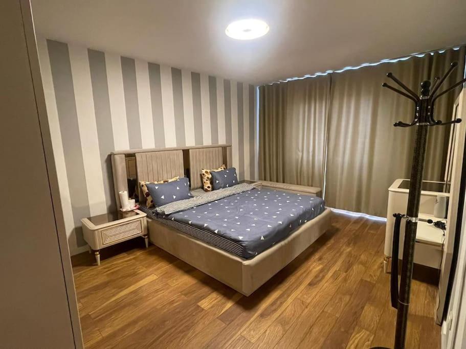 um quarto com uma cama com lençóis azuis e pisos em madeira em Pleasant apartment with panoramic view em Prizren